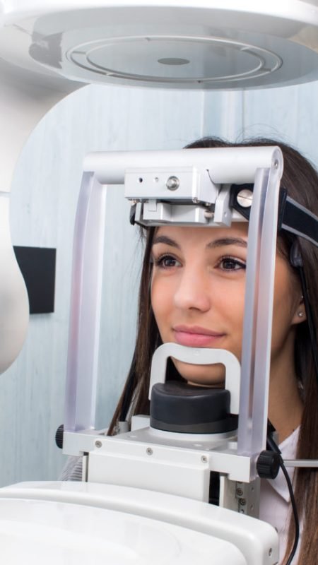 Close up head shot of girl taking dental tac with cephalometric panorama x-ray machine in clinic.